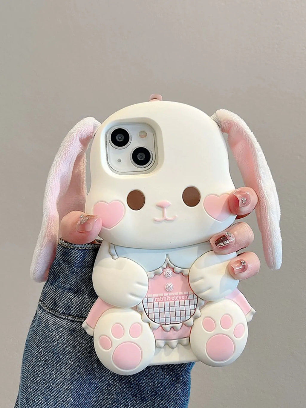 Phone case shaped like a cartoon bunny held by a person against a neutral background