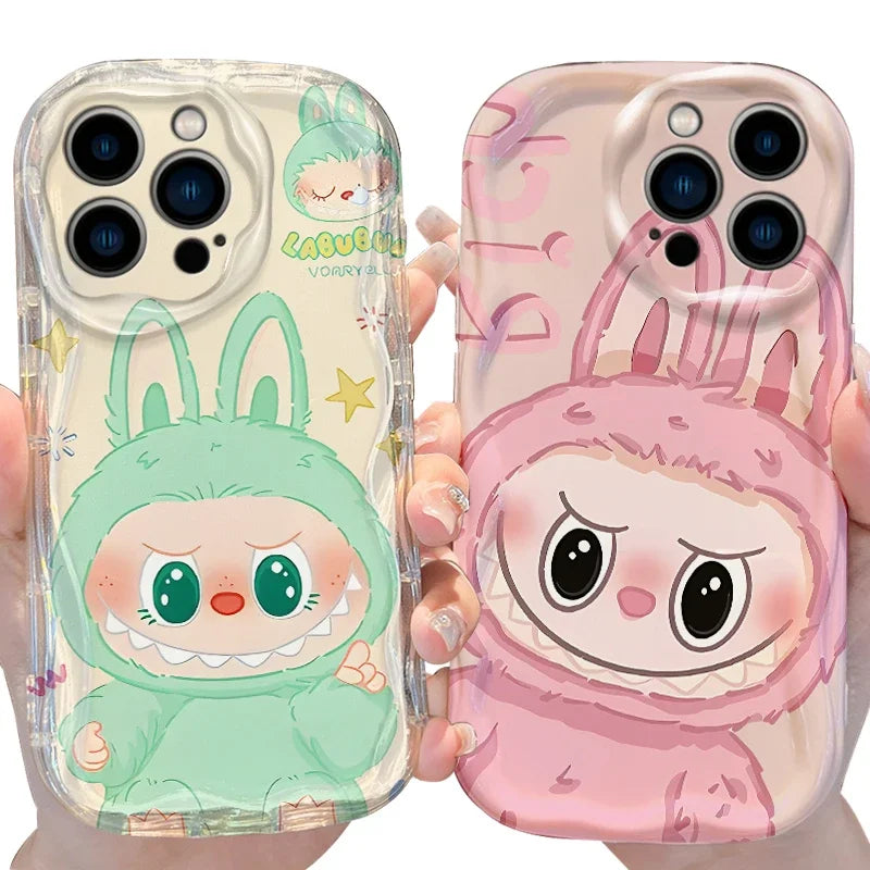 Two phone cases with cartoon characters, one green and one pink, held by a person.