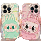 Two phone cases with cartoon characters, one green and one pink, held by a person.