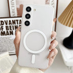 A hand holding a clear, geometric designed phone case with a magnetic attachment point for a Samsung Galaxy smartphone.