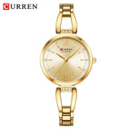 A gold-colored CURREN quartz wristwatch with a stainless steel band and rhinestone embellishments, displayed on a cream background.